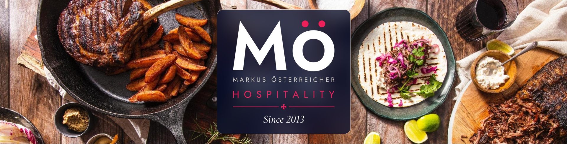 Gedeckter Tisch mit Steak, Taco und Beilagen und dem Logo von MÖ Hospitality